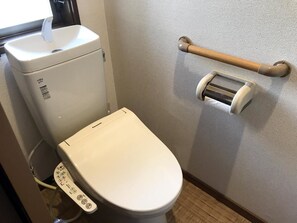 A toilet with a control panel, a toilet paper holder, and a bidet attachment. - Hananobou Bettei (Kyoto)