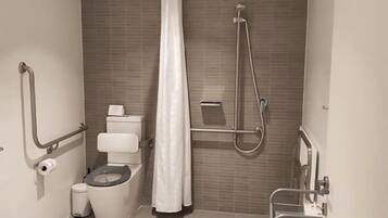 Un baño moderno con inodoro, ducha y barras de apoyo.