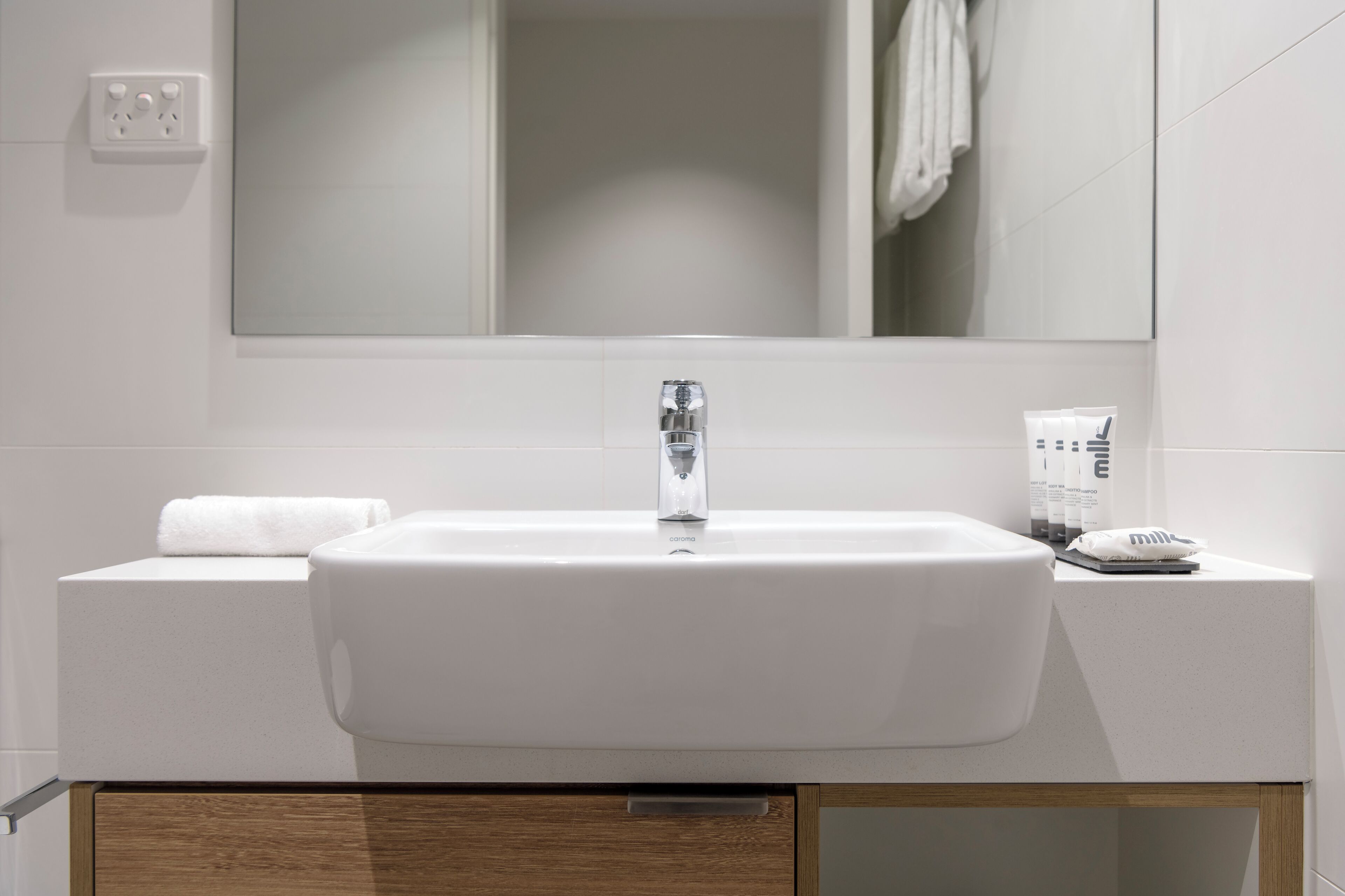 A modern bathroom with a white sink, a mirror above it, and a towel on the side.