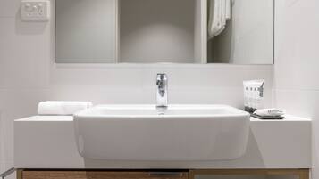 Un baño moderno con un lavamanos blanco, un espejo encima y una toalla al lado.