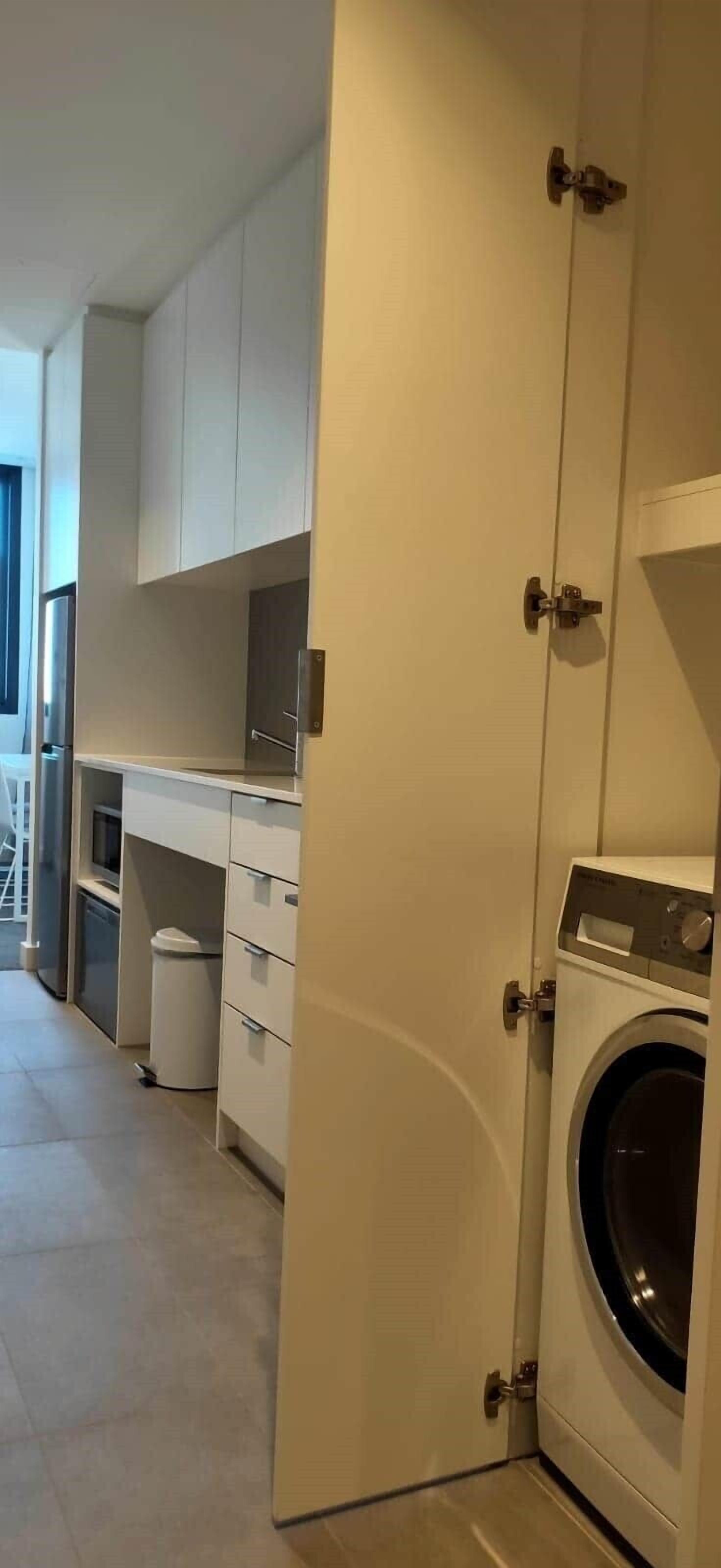 A laundry room with a washing machine, a dryer, and a small trash bin.