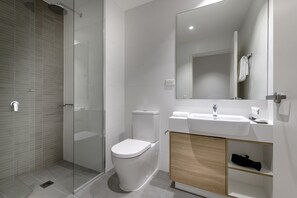 Une salle de bain moderne avec une douche à parois de verre, des toilettes blanches, un lavabo avec un miroir et un meuble en bois.