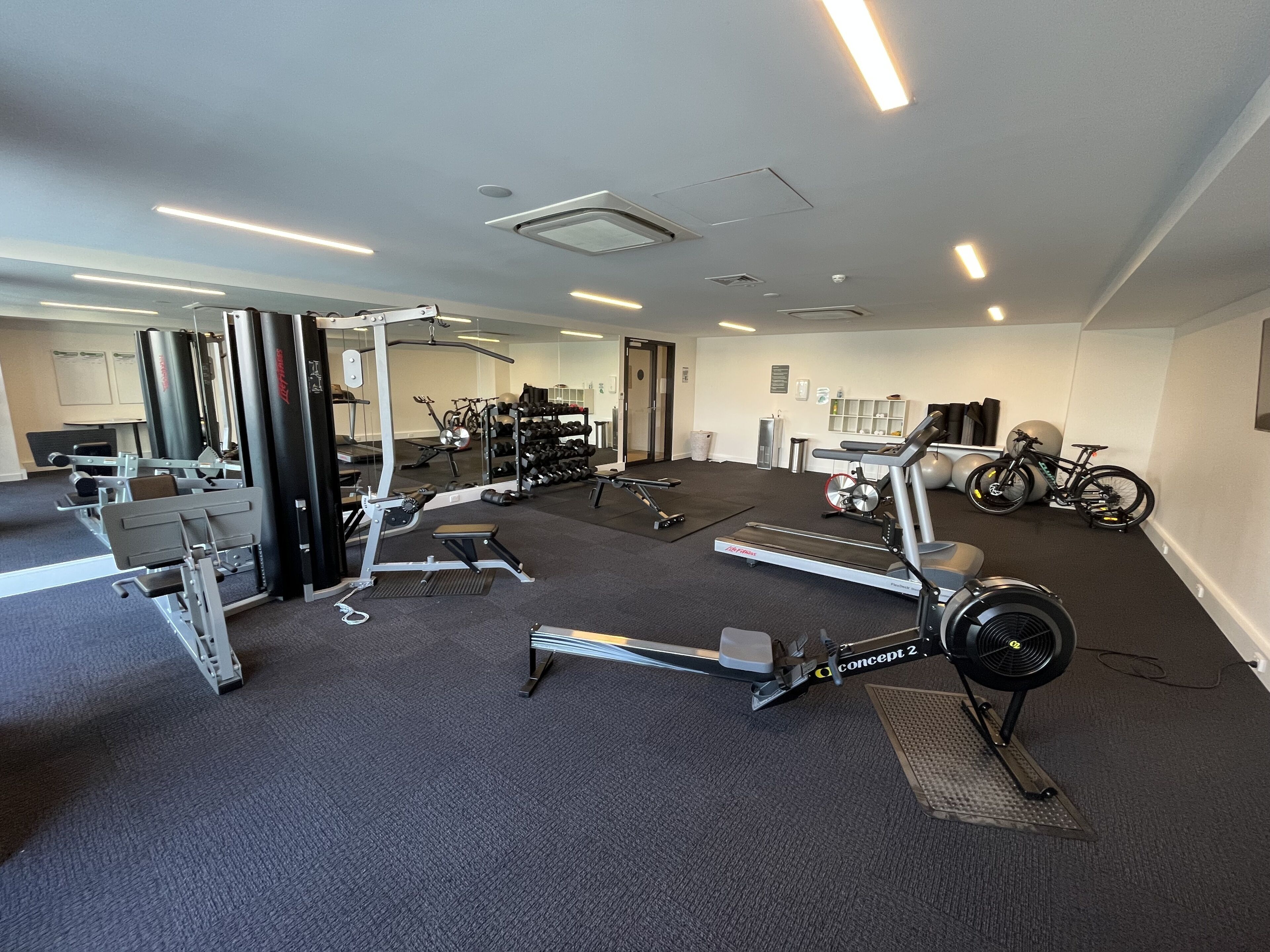 Un gimnasio con equipo cardiovascular, máquinas de pesas y bicicletas.
