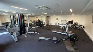 Un gimnasio con equipo cardiovascular, máquinas de pesas y bicicletas.