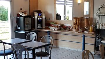A dining area with a counter, chairs, a refrigerator, and a coffee machine.
