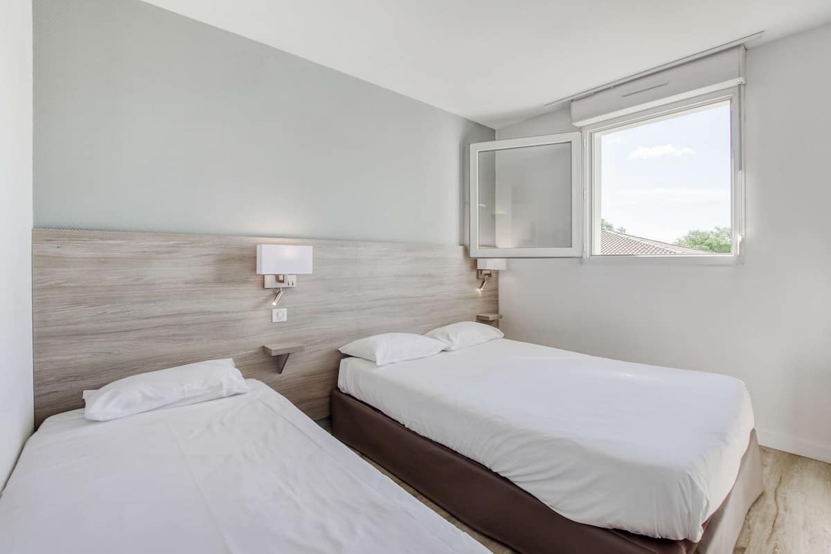 Ein Hotelzimmer mit zwei Betten, einem großen Fenster und Blick zum Himmel.