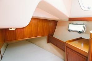 A compact, well-lit interior with a wooden bench, a small table, and a wall-mounted storage unit. - Sheliak boat and breakfast (Catania)
