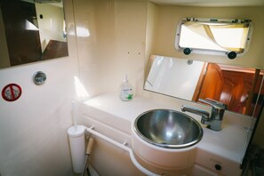A compact bathroom with a sink, mirror, and a small window. - Sheliak boat and breakfast (Catania)