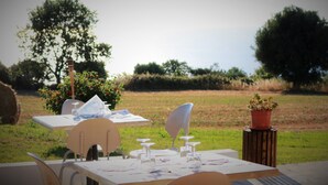 An outdoor dining area with tables set for two, surrounded by greenery and trees. - Agriturismo Ninea (Ricadi)