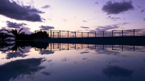 A bridge with a metal railing over a calm body of water, reflecting the sky and clouds. - Agriturismo Ninea (Ricadi)