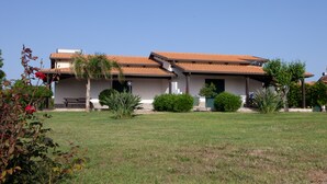 A two-story building with a tiled roof, a front porch, and a well-maintained lawn. - Agriturismo Ninea (Ricadi)