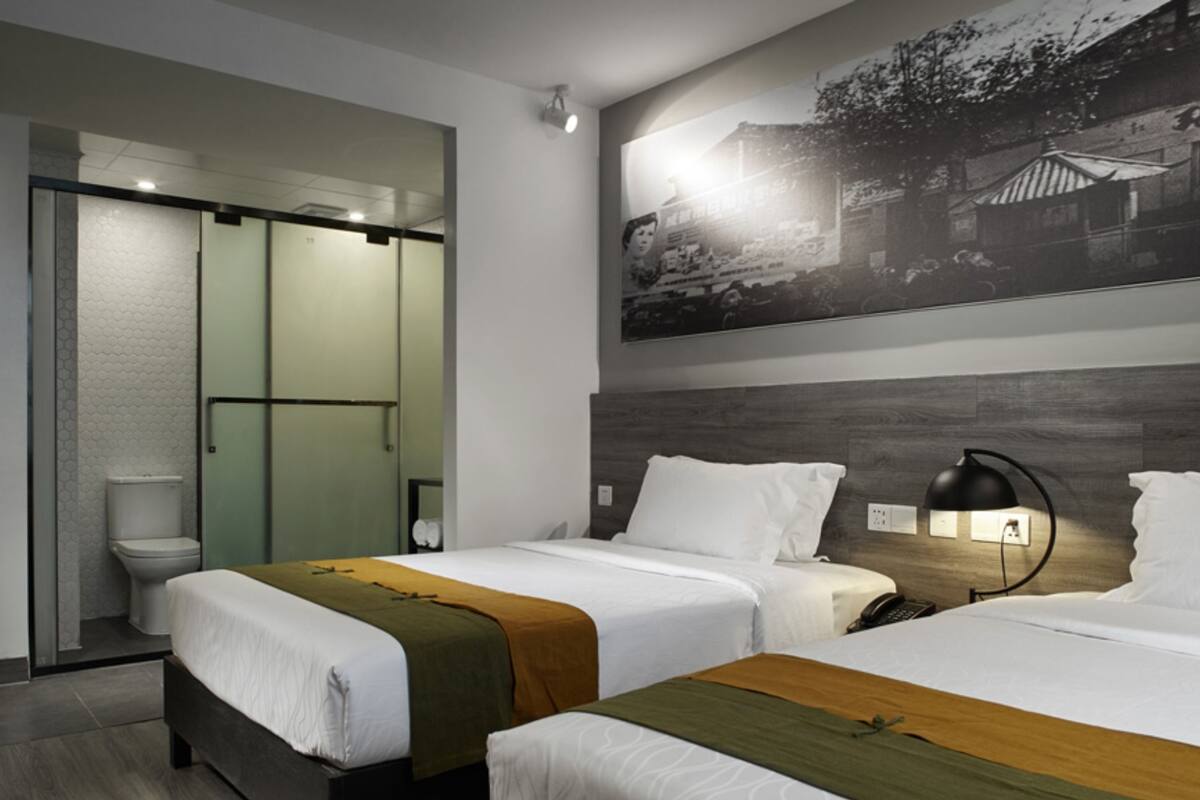 Une chambre d’hôtel avec deux lits, un espace douche et un grand tableau accroché au mur.