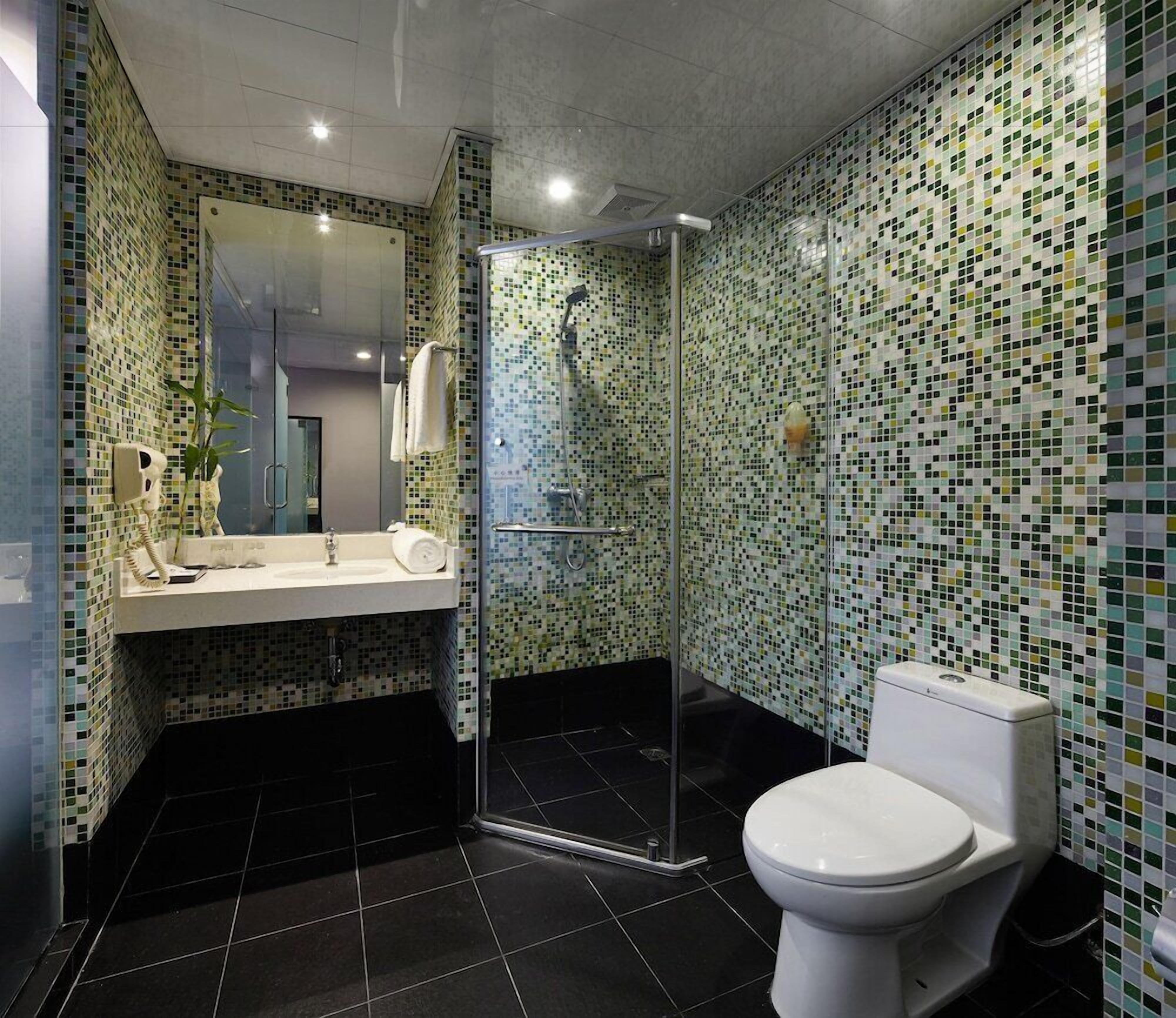 Een moderne badkamer met een douchecabine van glas, een wit toilet en een wastafel met spiegel.