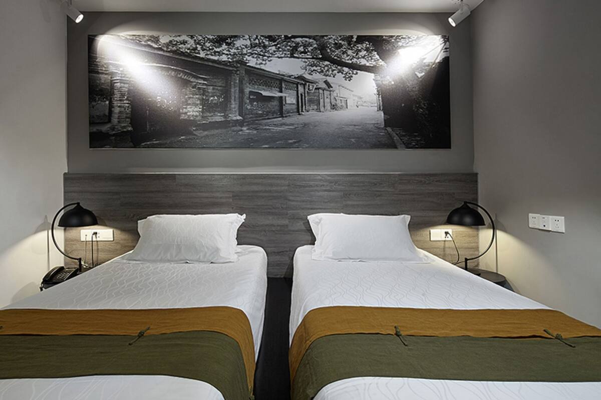 Une chambre d’hôtel avec deux lits, un grand tableau accroché au mur et deux lampes de chevet.