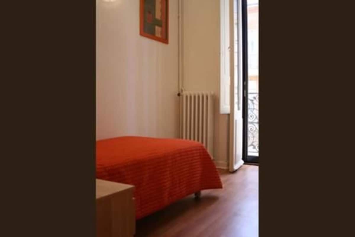 Une chambre à coucher avec un lit, un radiateur et une fenêtre donnant sur un beau paysage.