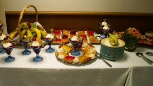 Een buffettafel met diverse desserts, fruit en een fruitmand.