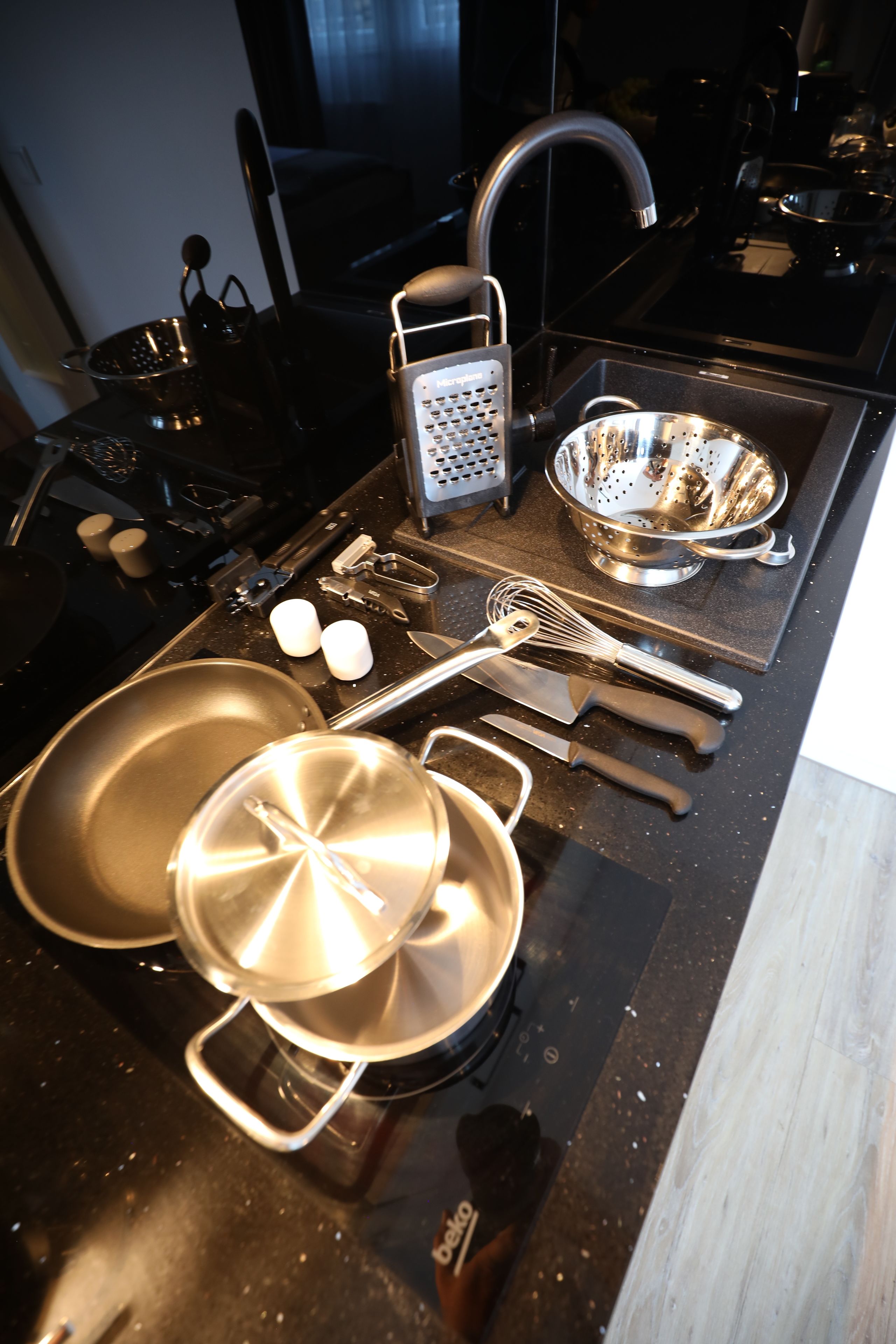 A kitchen with a stove, sink, and various cooking utensils.
