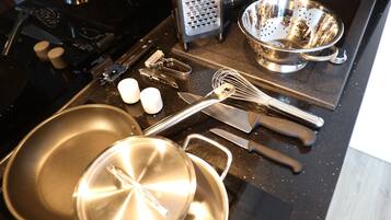 A kitchen with a stove, sink, and various cooking utensils.