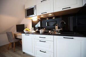 A modern kitchen with white cabinets, a black countertop, and a microwave above the stove.