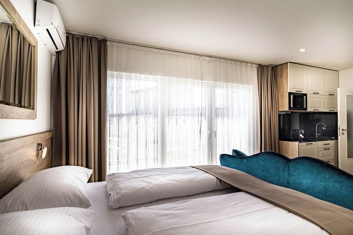 Une chambre d’hôtel avec un lit, un bureau équipé d’un ordinateur et une vue sur la ville grâce à de grandes fenêtres.