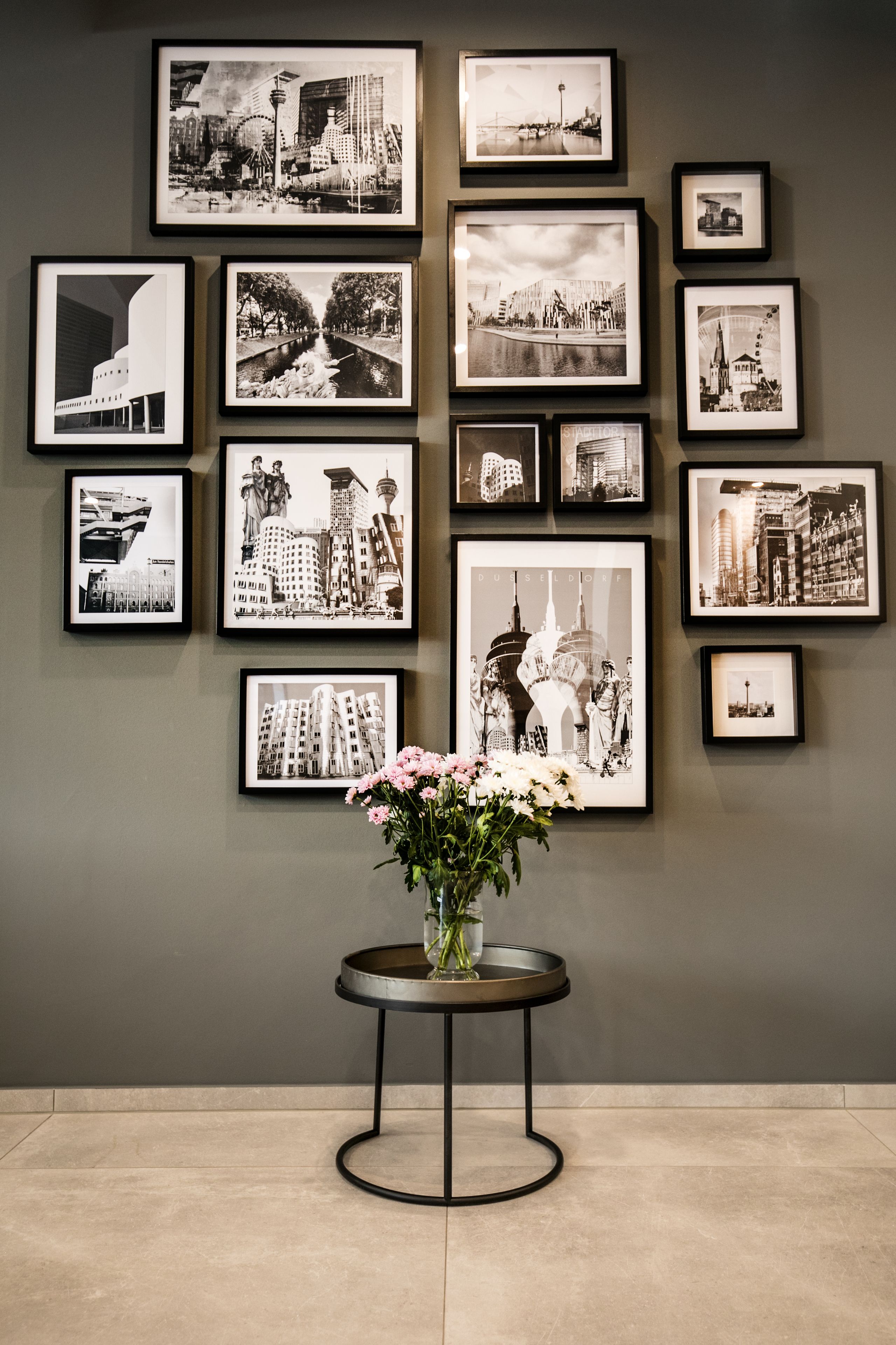 A wall with multiple framed black and white photographs of cityscapes and architectural structures.