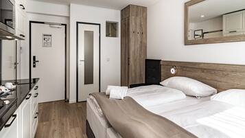 Une chambre d’hôtel moderne équipée d’un lit, d’une armoire, d’un miroir et d’un petit bureau avec une tasse et une soucoupe.
