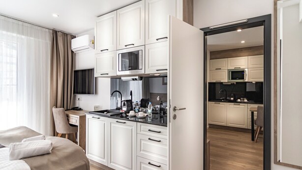 Habitació d'hotel moderna amb un llit, escriptori i una cuineta.