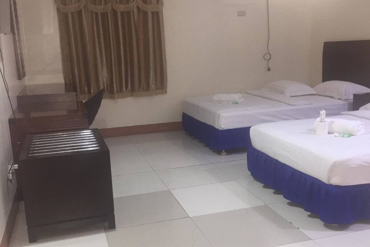Habitación de hotel con dos camas, un escritorio y un equipo de aire acondicionado.
