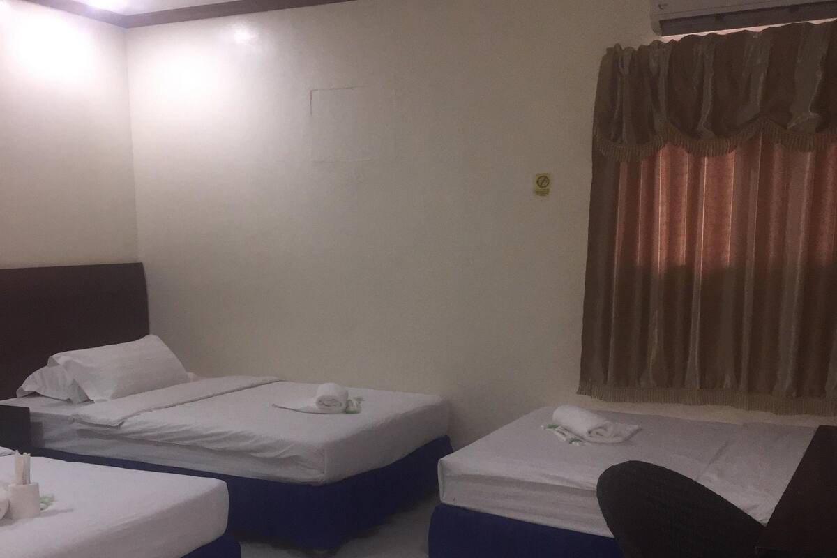 Habitación de hotel con dos camas individuales, un escritorio y una silla.