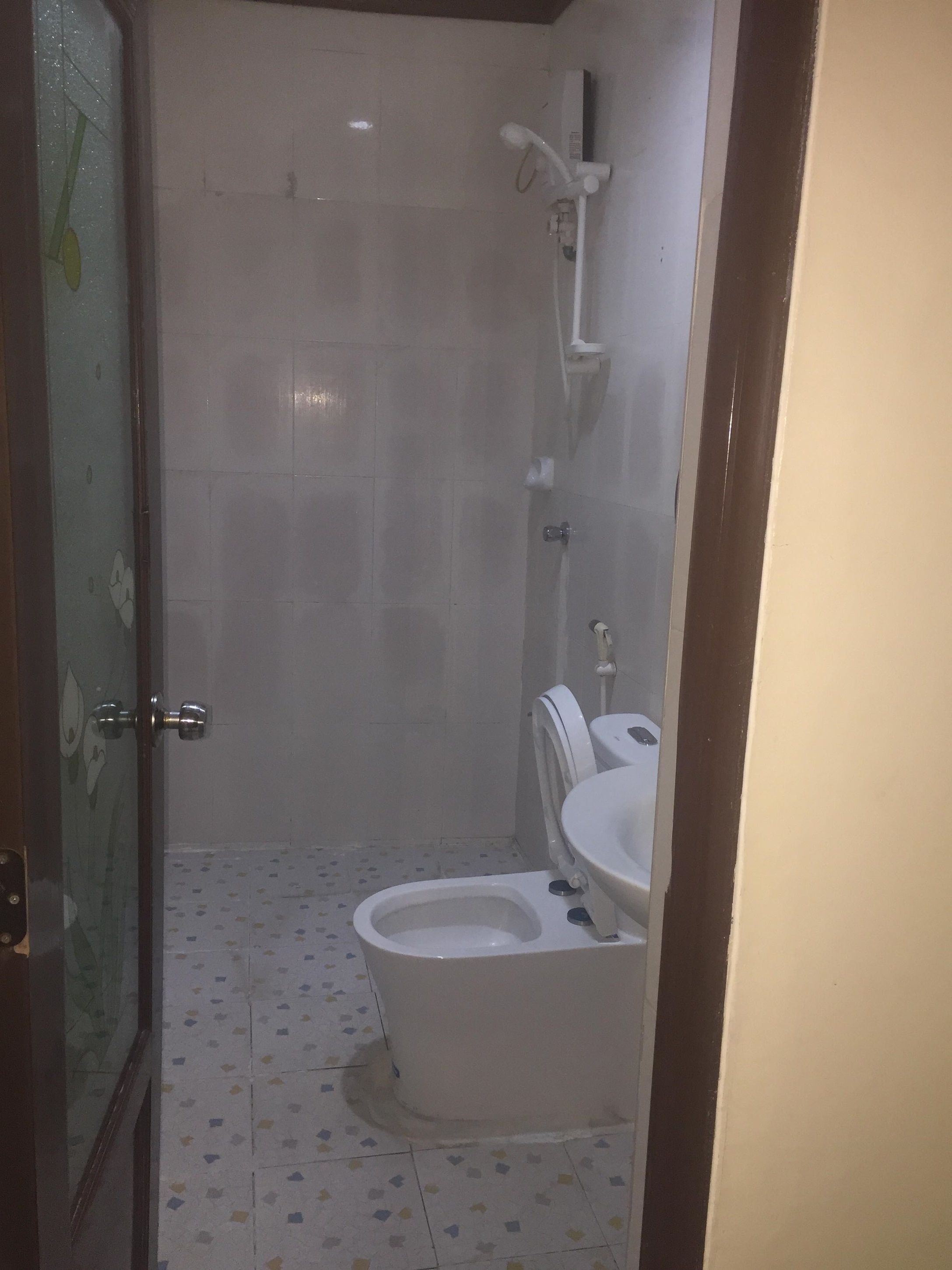 Un baño con inodoro, ducha y puerta de vidrio.