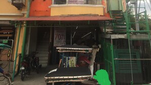 A building with a 'NOVO' sign, a 'HOTEL' sign, and a 'Consumer Value Trading Inc.' sign.