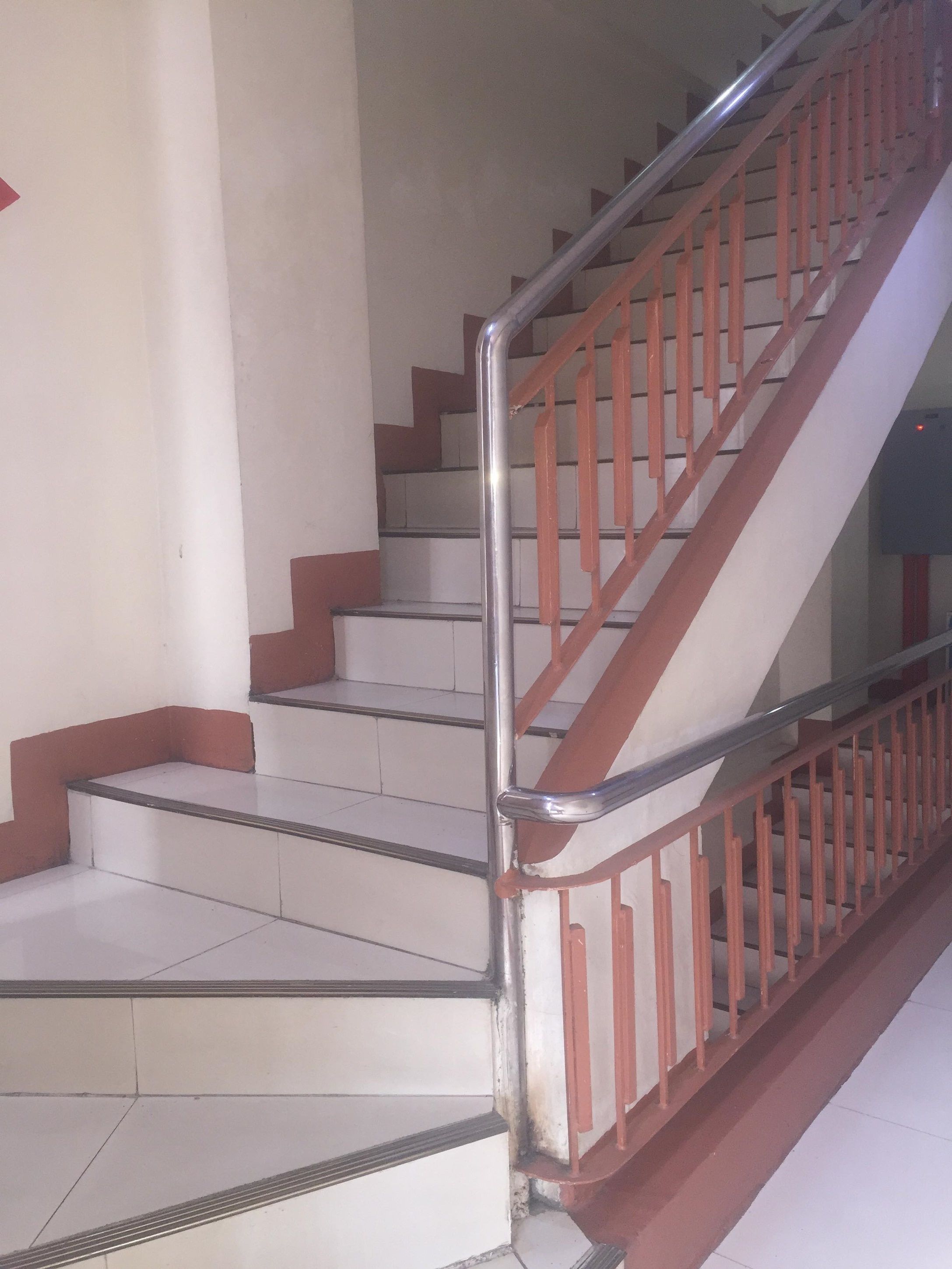 A staircase with metal handrails and red steps, leading to an upper floor.