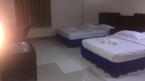 A hotel room with two beds, a desk, and an air conditioning unit.