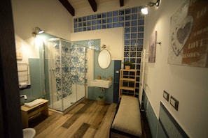A bathroom with a glass shower, a sink, a mirror, and a wooden bench. - B&B Cristiano (Rende)