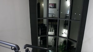 A staircase with a metal railing, a potted plant, and a dark-colored wall. - B&B Cristiano (Rende)