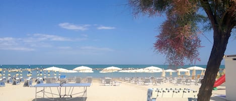Aan het strand, wit zand, ligstoelen aan het strand, parasols