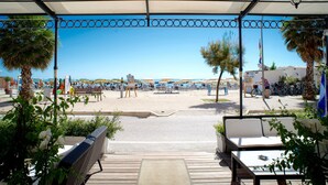 Un espace extérieur abrité avec des places assises, offrant une vue sur la plage, des parasols et des vélos.