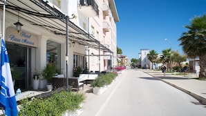Vue d’une rue où se trouve l’hôtel Baia Marina, avec une terrasse et des plantes en pot.