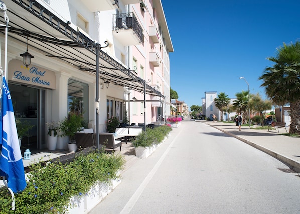 A street view of Hotel Baia Marina with outdoor seating and potted plants. - Baia Marina Hotel (Cupra Marittima)