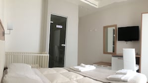 Une chambre d’hôtel avec un lit, une salle de bain, un miroir et une télévision.