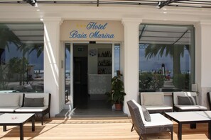 The entrance of Hotel Baia Marina with outdoor seating and a view of the sea. - Baia Marina Hotel (Cupra Marittima)