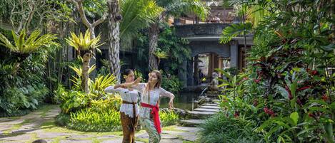 A lush garden with a stone pathway, tropical plants, and a water feature.