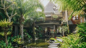 Een weelderige tuin met een vijver, een pad van stenen en tropische planten.