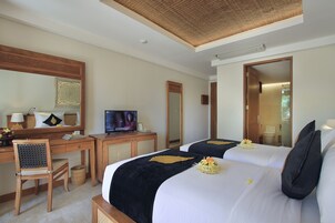 Une chambre d’hôtel avec deux lits, un bureau avec une télévision, une chaise et un miroir.