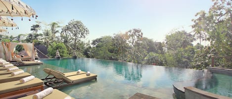 An infinity pool with lounge chairs and a wooden deck.