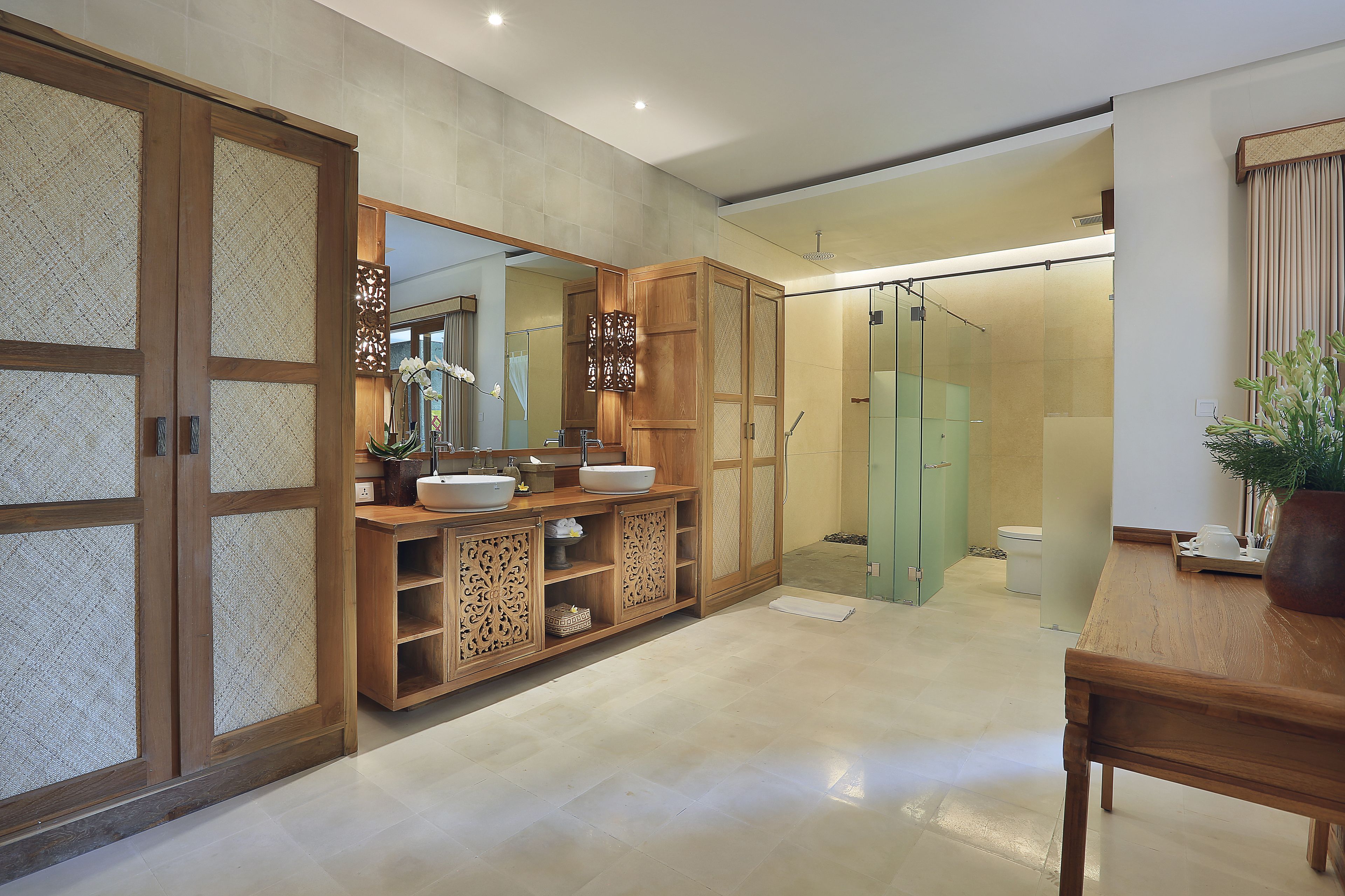 Une salle de bain moderne avec des meubles en bois, un grand miroir et une cabine de douche en verre.