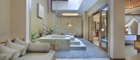 A modern interior with a sofa, a bathtub, and a glass partition.
