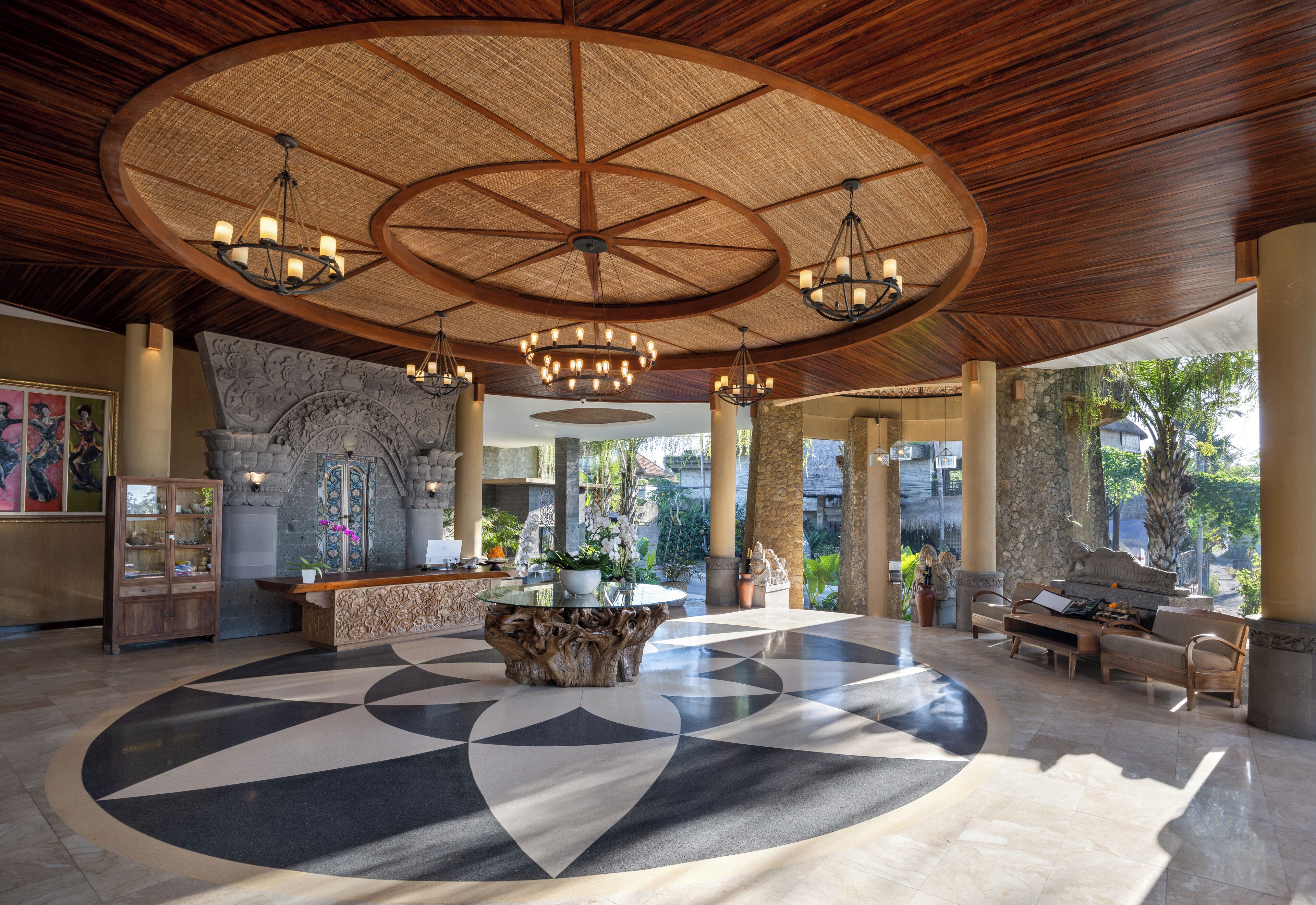 A spacious lobby with a central round table, a reception desk, and a seating area with a sofa and chairs.