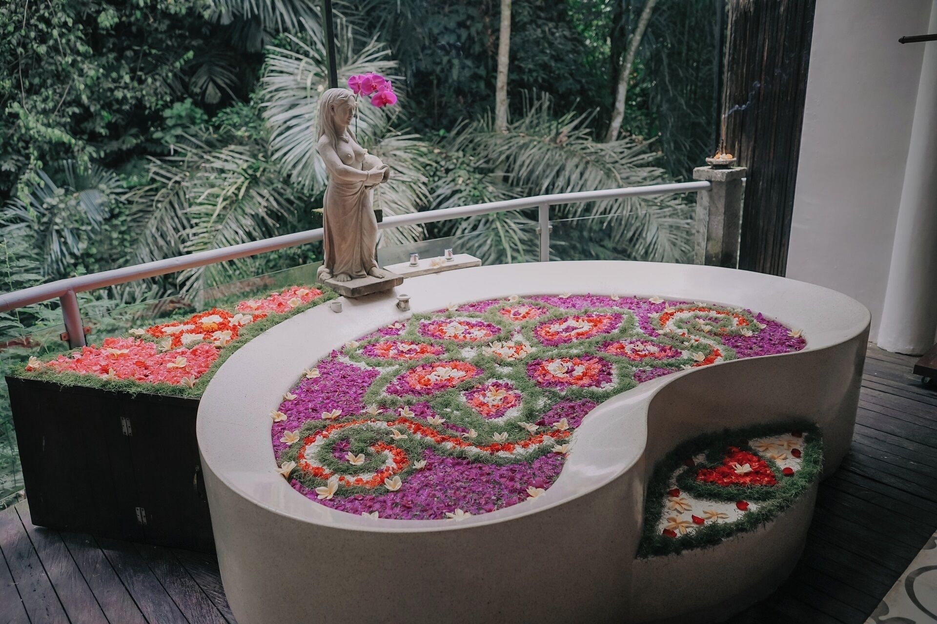 A bathtub with a floral design, a statue, and a railing.