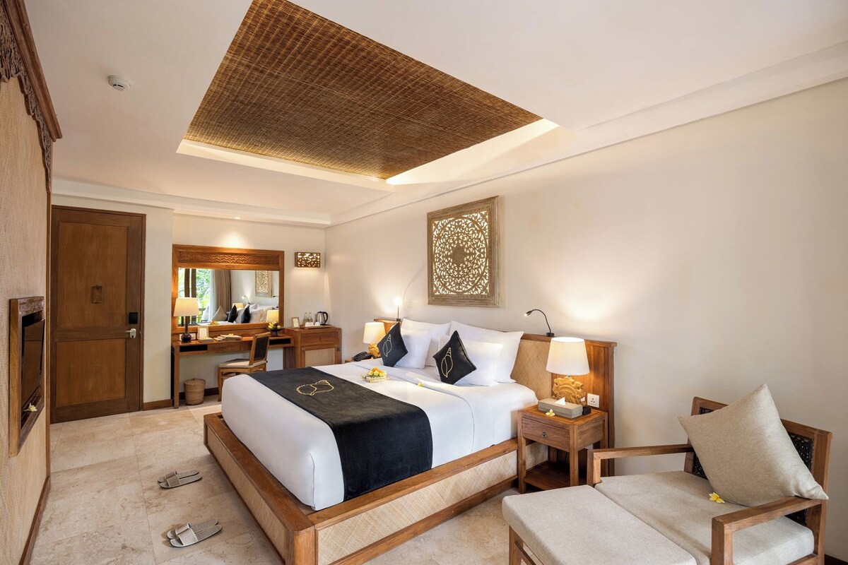 Une chambre d’hôtel avec un grand lit, un bureau, une chaise et un luminaire au plafond.